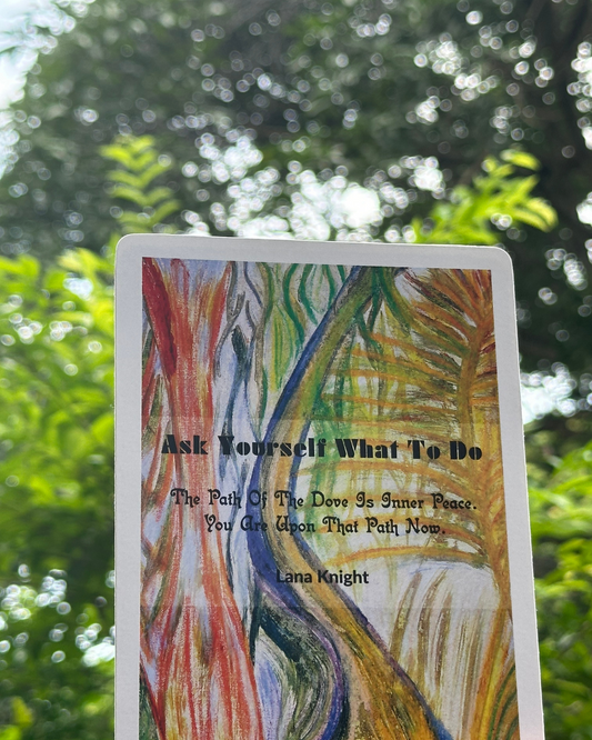 Cover of Ask Yourself What To Do Cards by Lana Knight. In the background are green leaved trees shining under sun light. A painting of a multicolored path way with foliage is used as the cover photo of the card deck. 
